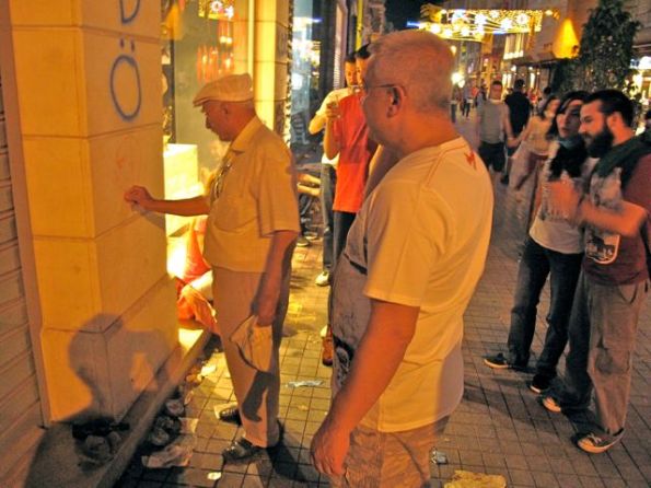 Group claps as an old man draws a picture on the wall of the Paşabahçe glassware shop of republican founder
